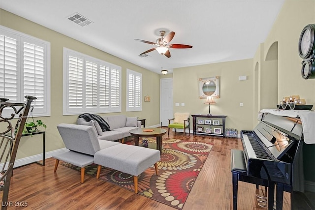 living room with a ceiling fan, visible vents, baseboards, and wood finished floors