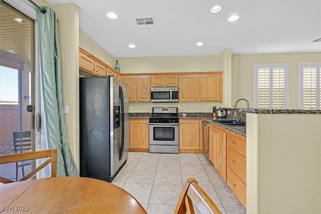 kitchen with light tile patterned floors, light brown cabinets, a sink, visible vents, and appliances with stainless steel finishes