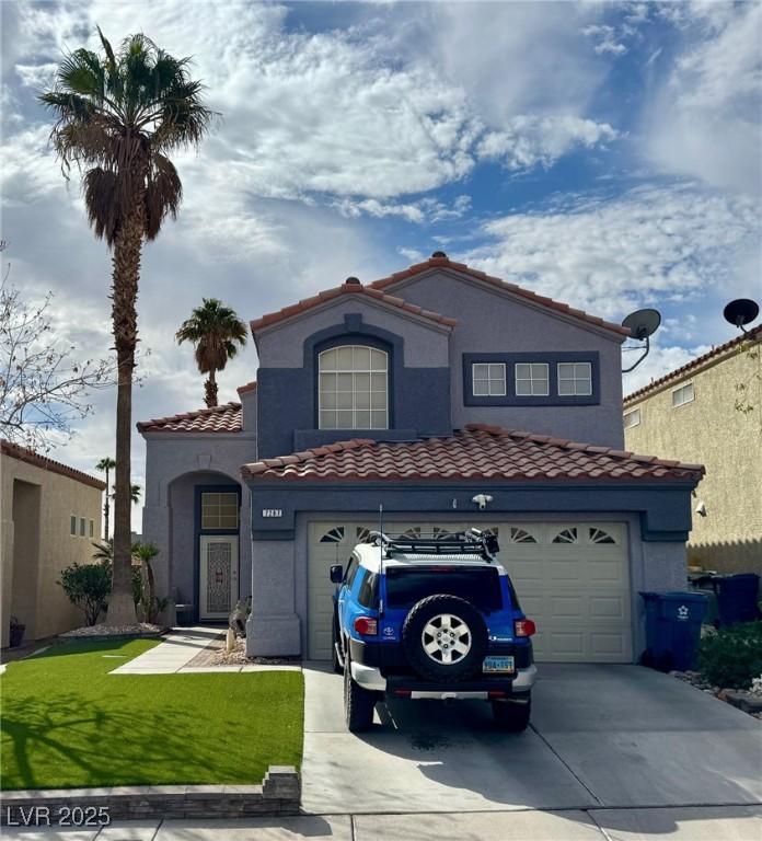 mediterranean / spanish house featuring driveway, a tiled roof, an attached garage, and stucco siding