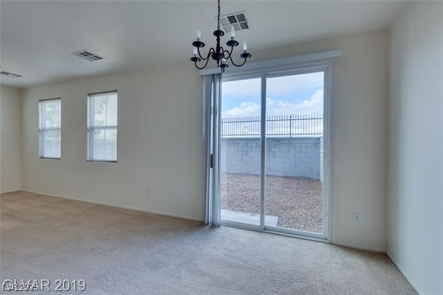 carpeted spare room with visible vents and a notable chandelier