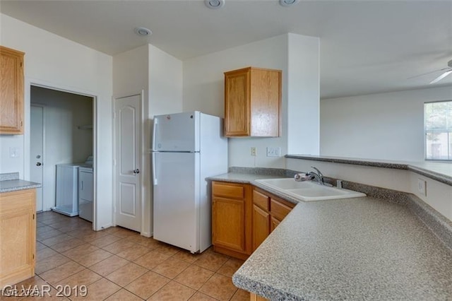 kitchen with light tile patterned floors, washer and clothes dryer, a ceiling fan, freestanding refrigerator, and a sink