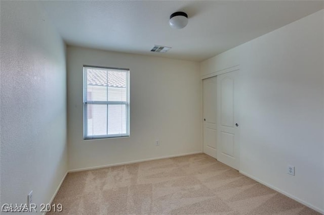 unfurnished bedroom with light carpet, a closet, and visible vents