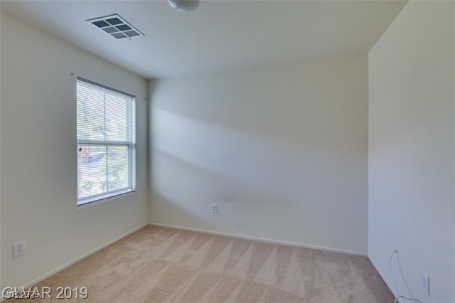 spare room with visible vents and light colored carpet