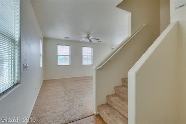 staircase with tile patterned flooring, ceiling fan, visible vents, and carpet flooring