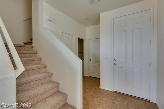 stairway with tile patterned flooring and visible vents