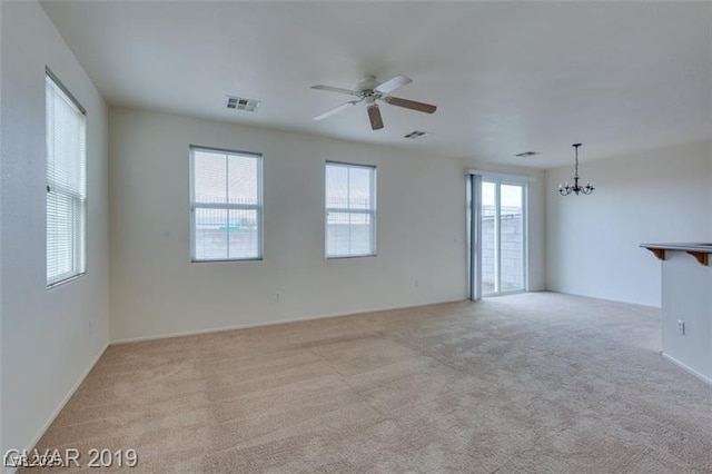 unfurnished living room featuring light carpet, ceiling fan with notable chandelier, and visible vents