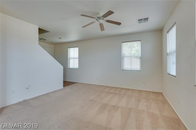 empty room with a ceiling fan, visible vents, and carpet flooring