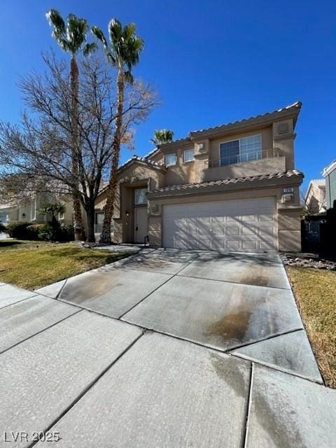 view of front facade with concrete driveway, an attached garage, a tiled roof, and stucco siding