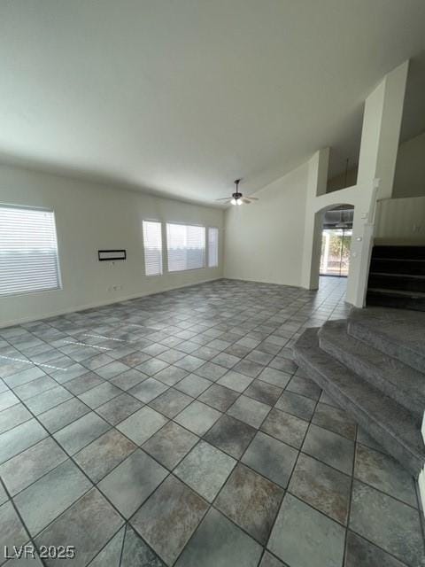 unfurnished living room featuring stairway, arched walkways, a ceiling fan, and tile patterned floors