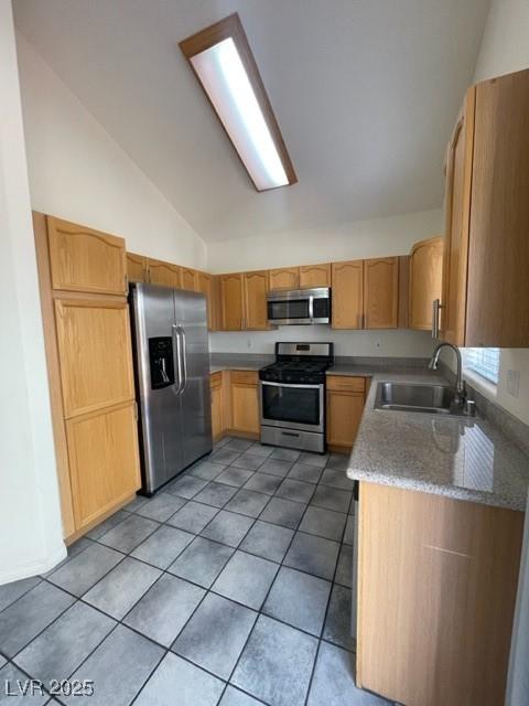 kitchen with light tile patterned floors, light stone counters, stainless steel appliances, a sink, and vaulted ceiling