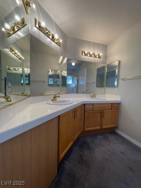 full bath featuring double vanity, baseboards, and a sink