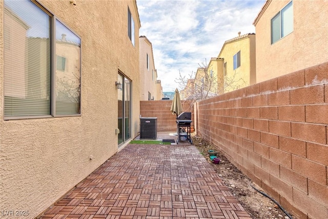 view of patio with a fenced backyard, a grill, and central AC