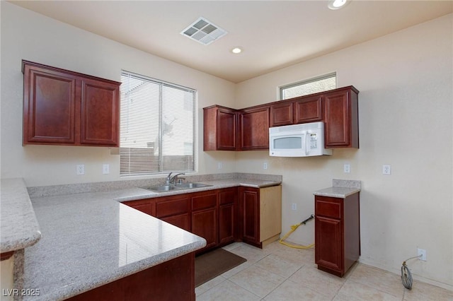 kitchen with white microwave, visible vents, light countertops, and a sink