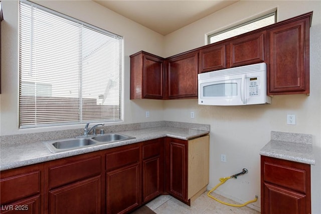 kitchen with white microwave, light countertops, and a sink