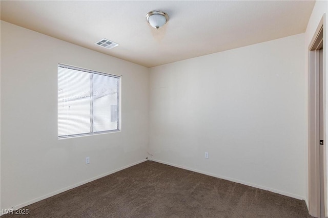 empty room with dark colored carpet, visible vents, and baseboards