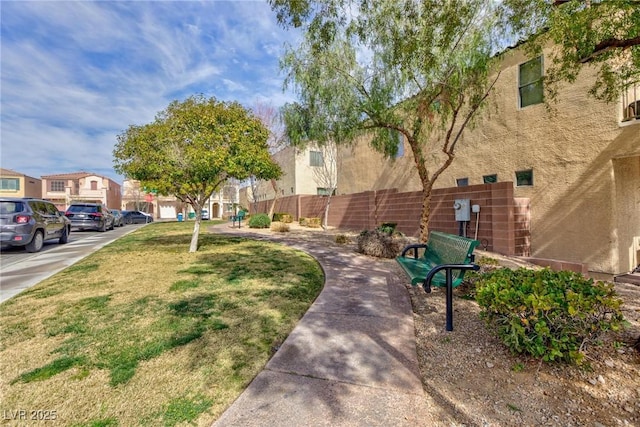 view of community featuring a lawn, fence, and a residential view