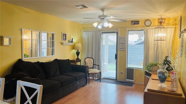 living area with a healthy amount of sunlight, ceiling fan, visible vents, and wood finished floors