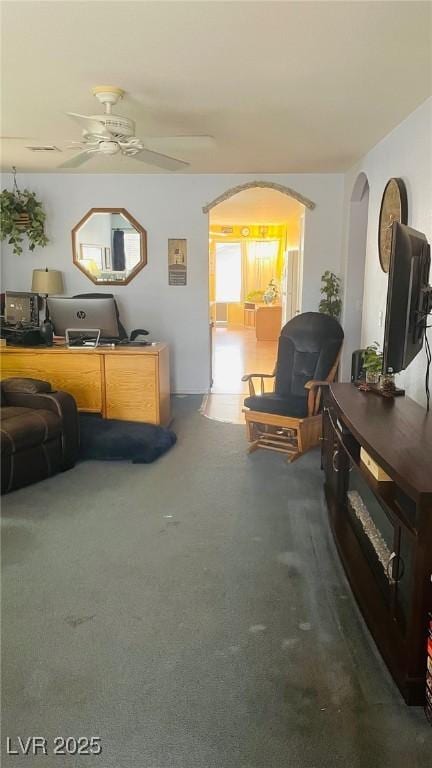 living room featuring arched walkways and ceiling fan