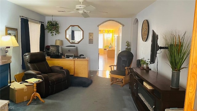 interior space with arched walkways, carpet floors, visible vents, and a ceiling fan