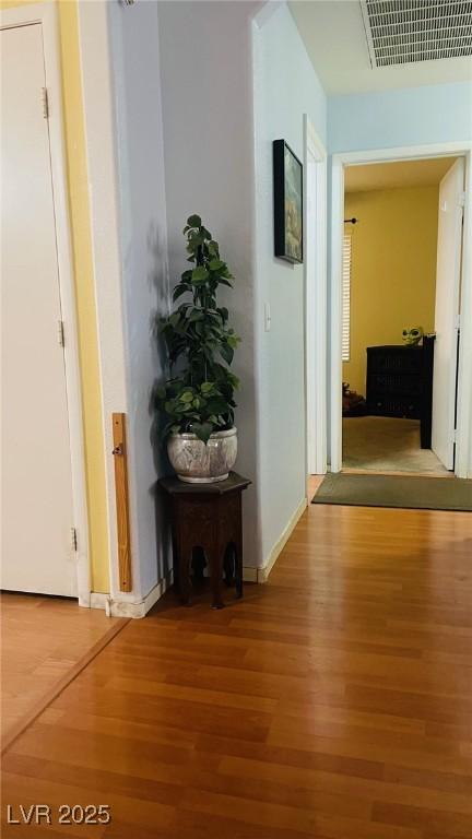 hallway featuring wood finished floors, visible vents, and baseboards