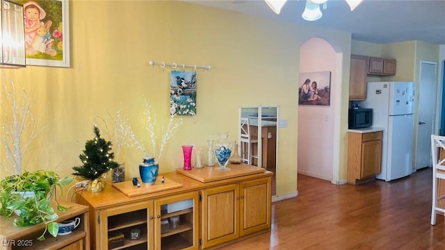 interior space with arched walkways, baseboards, and wood finished floors