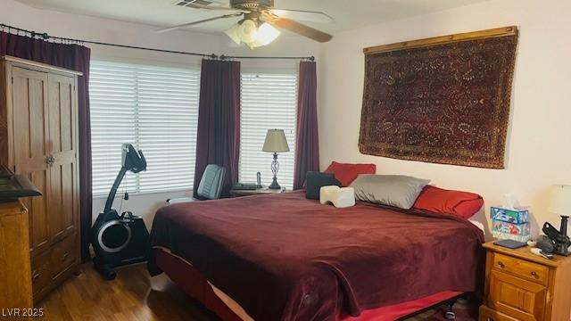 bedroom with ceiling fan, multiple windows, and wood finished floors