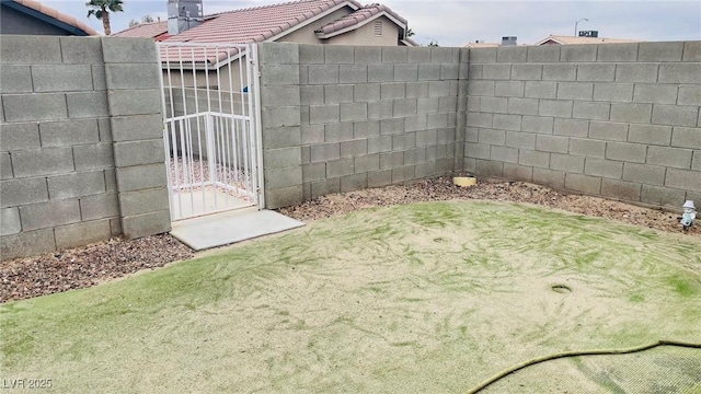 view of yard with a fenced backyard and a gate