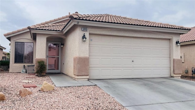 mediterranean / spanish-style house featuring an attached garage, a tile roof, concrete driveway, and stucco siding