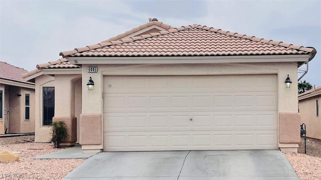 mediterranean / spanish-style house with a garage, a tiled roof, concrete driveway, and stucco siding