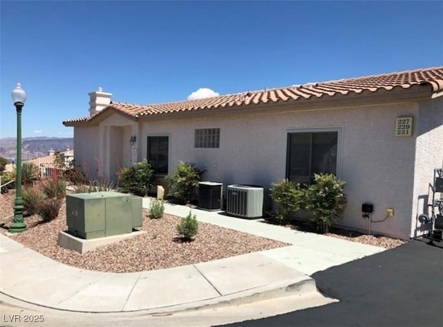 view of front of home featuring central air condition unit, a tile roof, and stucco siding