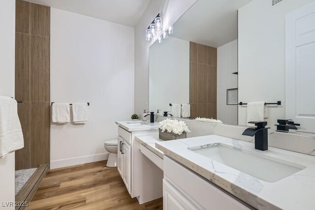 full bathroom with a sink, toilet, wood finished floors, and double vanity