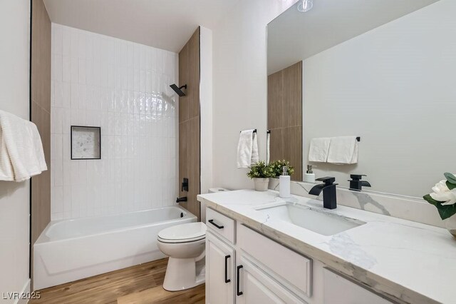 bathroom with tub / shower combination, toilet, vanity, and wood finished floors