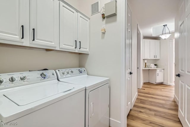 laundry area featuring washing machine and clothes dryer, visible vents, baseboards, light wood-style floors, and cabinet space