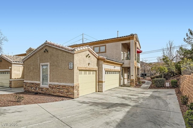 view of front of property featuring stone siding, stucco siding, concrete driveway, and a balcony