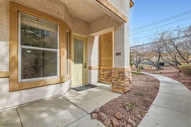 doorway to property with stone siding and stucco siding