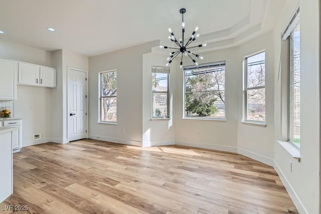 unfurnished dining area featuring recessed lighting, a notable chandelier, baseboards, and light wood-type flooring