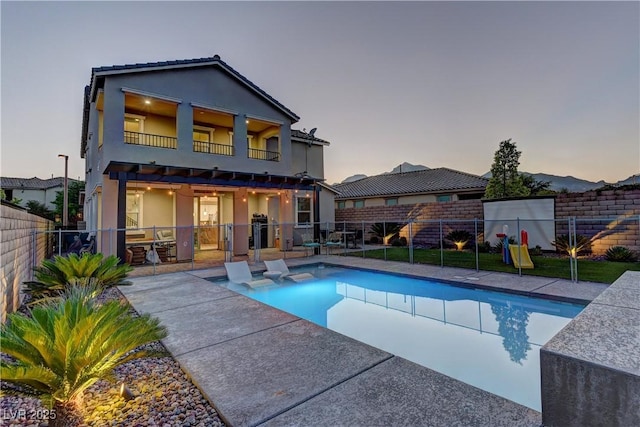 rear view of house with a patio area, a fenced backyard, a balcony, and a fenced in pool