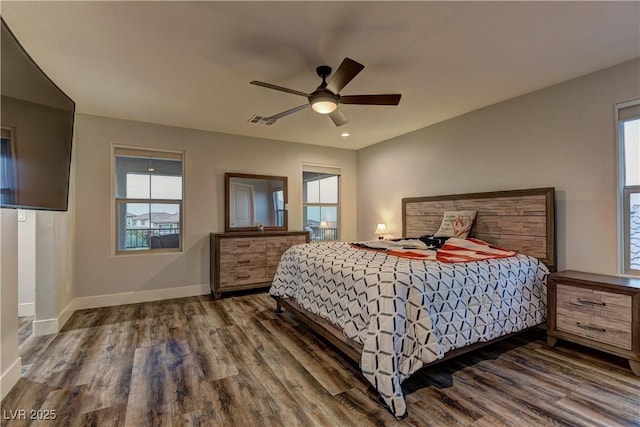 bedroom with a ceiling fan, visible vents, baseboards, and wood finished floors