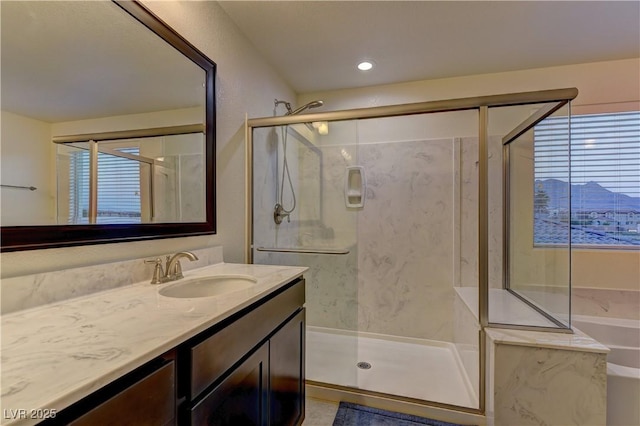 full bathroom with a tub with marble appearance, a marble finish shower, vanity, and a healthy amount of sunlight