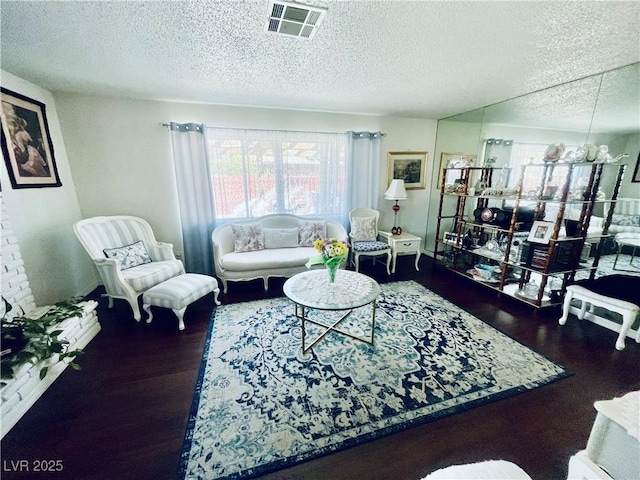 living area with a textured ceiling, wood finished floors, and visible vents