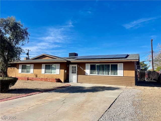 single story home featuring fence and solar panels