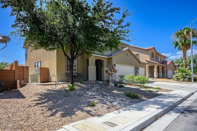 mediterranean / spanish home with a tile roof, stucco siding, an attached garage, fence, and driveway