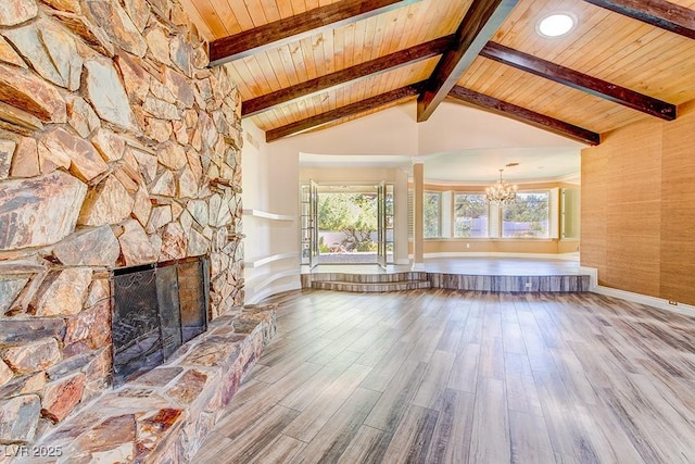 unfurnished living room with vaulted ceiling with beams, a fireplace, wood finished floors, a chandelier, and wooden ceiling