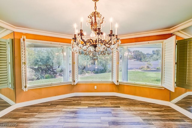 unfurnished dining area featuring baseboards, a chandelier, wood finished floors, and ornamental molding