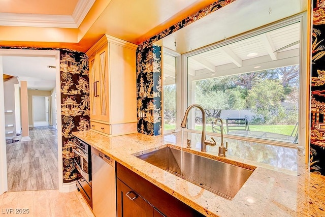 kitchen featuring crown molding, light wood finished floors, a sink, light stone countertops, and dishwasher