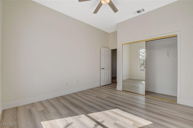 unfurnished bedroom featuring a closet, visible vents, a ceiling fan, wood finished floors, and baseboards