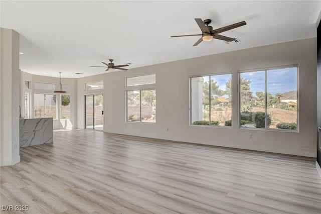 unfurnished living room with a healthy amount of sunlight, light wood-style flooring, and visible vents