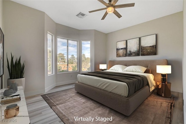 bedroom featuring baseboards, a ceiling fan, visible vents, and light wood-style floors