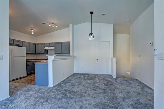 kitchen featuring lofted ceiling, freestanding refrigerator, gray cabinets, under cabinet range hood, and dark carpet