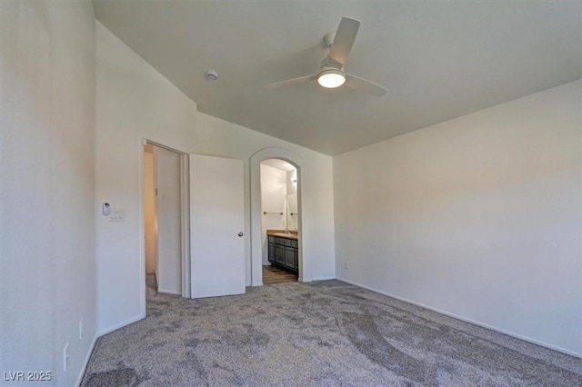 unfurnished bedroom with arched walkways, carpet floors, ensuite bath, and a ceiling fan